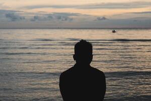 Silhouette of a Man on the Beach at Sunset photo