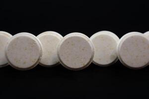 White pills on a black background. Focus on foreground, shallow depth of field. photo