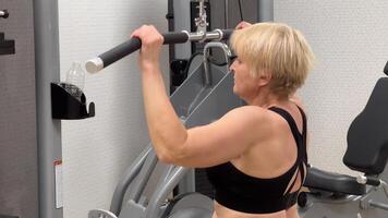 An individual is engaged in an intense workout session using a cable pulley machine at the gym against a geometrically patterned backdrop. photo