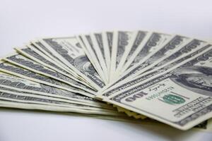 A closeup shot of a stack of new, hundred-dollar bills fanned out on a plain white background photo
