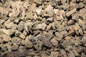 A close up image of a pile of crushed stone with varying shades of gray and brown. The stone is likely used for landscaping or construction purposes photo