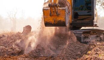Close-up of excavator at construction site. Backhoe digging soil for earthwork and construction business. Excavating machine at work. Heavy machinery for earth moving and construction site development photo