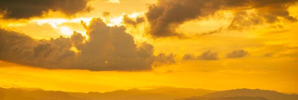 Beautiful sunset with a cloudy sky. The sky is a mix of yellow and orange colors. The clouds are scattered throughout sky, creating a sense of depth and movement. Golden sky background. Cloudscape. photo