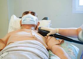 Closeup hands of doctor using electrical muscle stimulation on shoulder of elderly patient in nursing homes photo