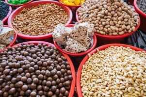 assortment of different varieties of nuts, dried fruits and Uzbek halva on counter at the oriental food bazaar in market stall photo