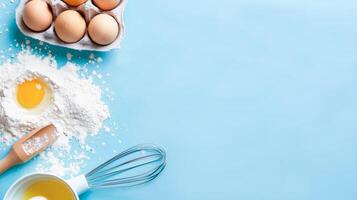 Baking concept. Blue background with eggs, flour and dough kneading tools. photo