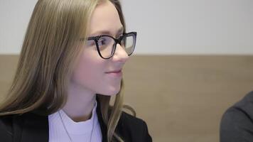 Close-up of a young woman in glasses sitting at a meeting and listening attentively. Office employee of the company. video