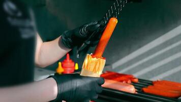 Close-up of cooking Hod Dog in a fast food restaurant. An employee stuffs a sausage into a bun with sauces video