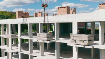 The builder fixed the load that will be lifted by the lifting crane. Construction of a brick and monolith house. video