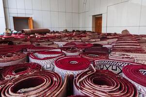 stack of rolled up traditional vintage Uzbek red carpets oriental bazaar for sale in Tashkent in Uzbekistan photo
