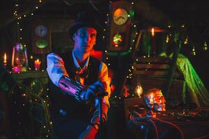 portrait of male inventor in a steampunk suit, a top hat with a cane in hand sits in a watch workshop photo