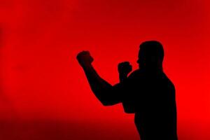 Silhouette of a strong fighter practicing combat exercises photo
