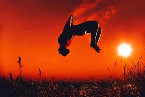 man jumps and does a back flip in the summer in nature photo