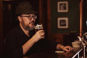 man drinks beer from a glass at bar photo
