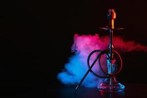 hookah with a glass flask and a metal bowl shisha with colored smoke on the table photo
