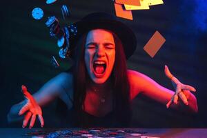 woman throws up cards and chips at a poker table in a casino photo