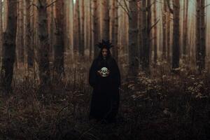 terrible witch holds the skull of a dead man in her hands photo