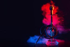 hookah with a glass flask and a metal bowl shisha with colored smoke on the table photo