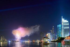 Celebration with fireworks light up sky over business district in Ho Chi Minh City, Vietnam. Beautiful night view cityscape. Holidays, independence day, New Year and Tet holiday photo