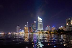 Ho Chi Minh City skyline and the Saigon River. Amazing colorful night view of skyscraper and other modern buildings at downtown. Travel concept photo