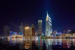 Ho Chi Minh City skyline and the Saigon River. Amazing colorful night view of skyscraper and other modern buildings at downtown. Travel concept photo