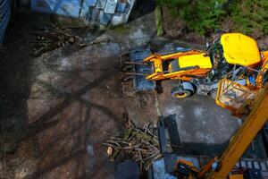 A bulldozer collects branches after pruning trees. View from above photo