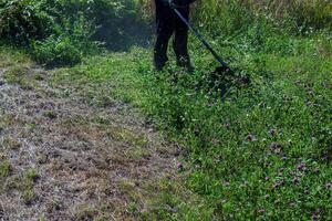 A man cuts and mows the grass. Grass cutting work. Worker mows lawn with grass photo