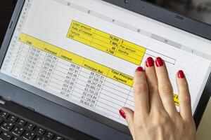 Close up shot of the woman with beautiful hands and manicure, working on the laptop, scrolling touch screen with mortgage loan amortization table open. Banking photo