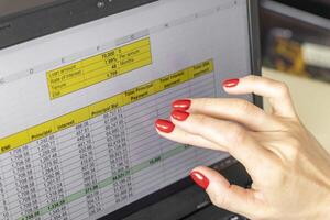 Close up shot of the woman with beautiful hands and manicure, working on the laptop, scrolling touch screen with mortgage loan amortization table open. Finance photo