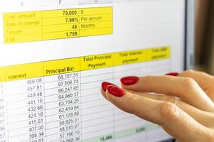 Close up shot of the woman with beautiful hands and manicure, working on the laptop, scrolling touch screen with mortgage loan amortization table open. Finance photo