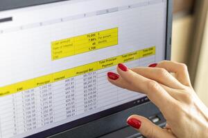 Close up shot of the woman with beautiful hands and manicure, working on the laptop, scrolling touch screen with mortgage loan amortization table open. Finance photo