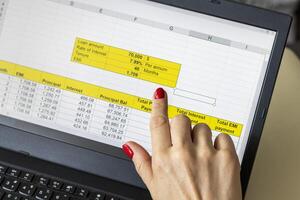 Close up shot of the woman with beautiful hands and manicure, working on the laptop, scrolling touch screen with mortgage loan amortization table open. Banking photo