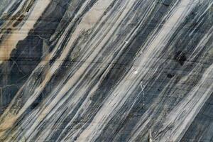 Detailed close-up of marble rock showcasing its natural striations and texture. The image captures the intricate patterns and colors within the stone, highlighting the beauty of natural geology. photo