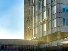 A modern office building bathed in the warm light of sunset, with a red balloon in the foreground. The serene sky and soft lighting create a peaceful urban scene. photo