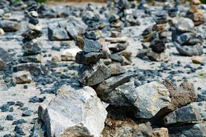 Close-up of a pile of stacked stones on a rocky terrain. The image captures the balance and arrangement of various rocks, showcasing the art of stone stacking in a natural outdoor setting. photo