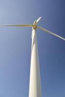 Close-up and low angle view of spinning blades of a wind turbine generating renewable energy photo