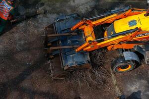 Dnepr, Ukraine - 03.20.2024 A bulldozer collects branches after pruning trees. View from above photo