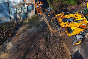 Dnepr, Ukraine - 03.20.2024 A bulldozer collects branches after pruning trees. View from above photo