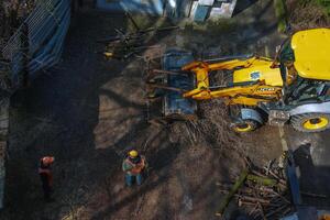 Dnepr, Ukraine - 03.20.2024 A bulldozer collects branches after pruning trees. View from above photo