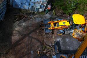 Dnepr, Ukraine - 03.20.2024 A bulldozer collects branches after pruning trees. View from above photo
