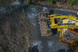 Dnepr, Ukraine - 03.20.2024 A bulldozer collects branches after pruning trees. View from above photo