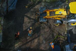 Dnepr, Ukraine - 03.20.2024 A bulldozer collects branches after pruning trees. View from above photo