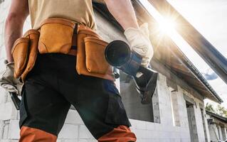 Construction Worker With Tool Belt and Gutter Element in His Hand photo