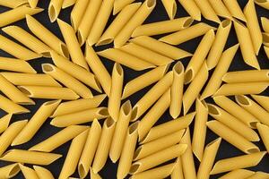 Penne rigate pasta pattern on black background, top view, flat lay texture photo