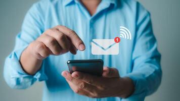 Online communication, online marketing, data link tech, Businessman holding smartphone and touching with virtual icon white newsletter for electronic mail or E-mail with notification alert. photo