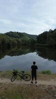Man Resting with His Bicycle by the Lake, Enjoying the Beautiful Summer Morning Background photo