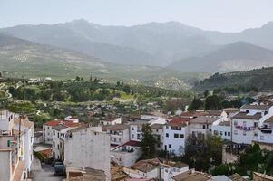 View of beautiful medieval district of Spanish village, Quesada in the region of Jaen, Andalusia Spain in mountains. White houses with red tiles over mountain ridge background of La Sierra de Cazorla photo