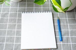 An empty mock up notebook with a pen on a table with home potted plants. Recording recommendations for plant care photo