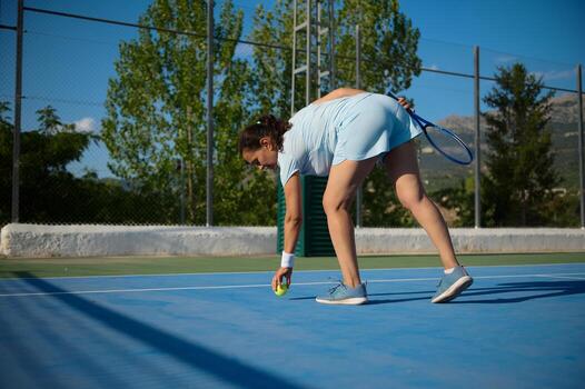 Middle-aged woman playing tennis on outdoor court under sunny sky photo