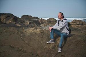 Man sitting on rocks at the beach, enjoying the ocean view and peaceful moment photo